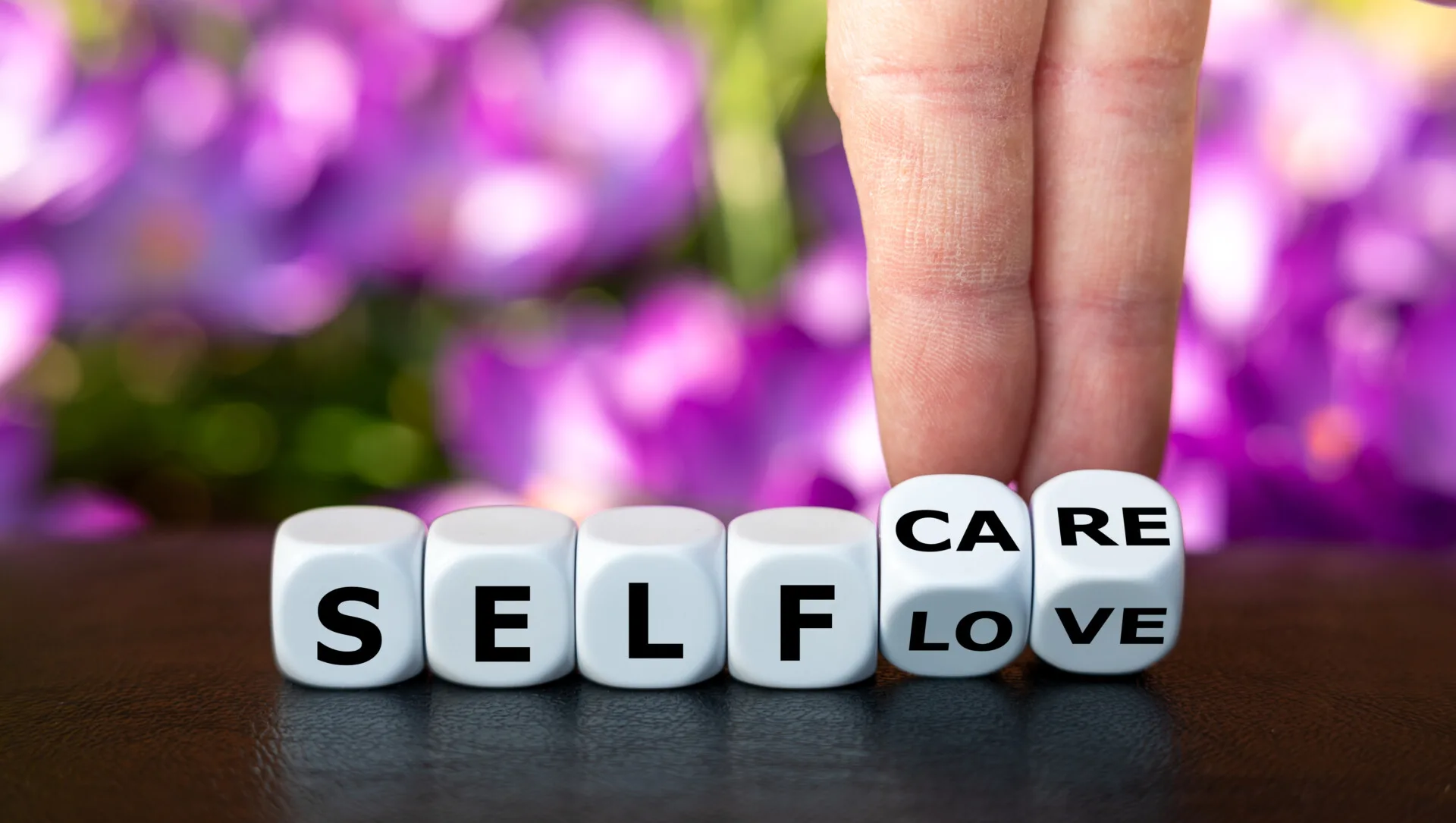 Eine Hand dreht Buchstabenwürfel um. Die Worte Love wechseln zu Care. - Helfersyndrom überwinden